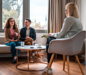 Two parents sit on the couch in a therapy office talking to a psychologist. Parents in SPACE therapy learn skills to help their teenager cope with anxiety and OCD.