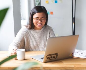 Woman sitting at table with laptop. Dr. Penela provides online therapy to help children and adults overcome anxiety and OCD.