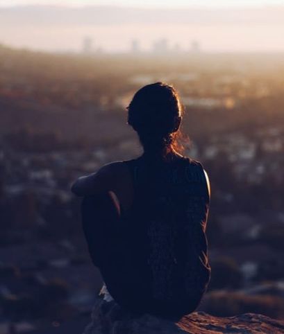 Woman sitting on mountaintop. Learn to overcome anxiety with CBT tools.