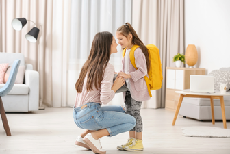 Mother squats down to see daughter at eye-level and they smile at each other. Validating a child's emotions helps them feel understood.