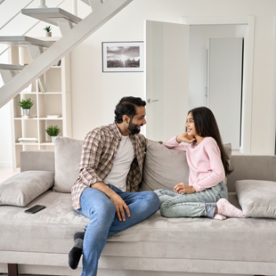 A girl smiles while talking with her mother and father as they sit together. In CBT therapy, parents learn skills to help their child cope with anxiety and OCD.