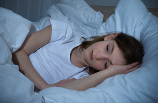 Child lays and worries in bed. As children prepare to return to school after an extended break, it's normal to feel sadness and anxiety.
